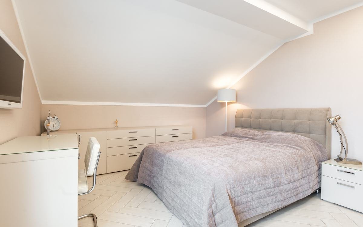 Finished loft conversion bedroom with sloping ceiling and roof window